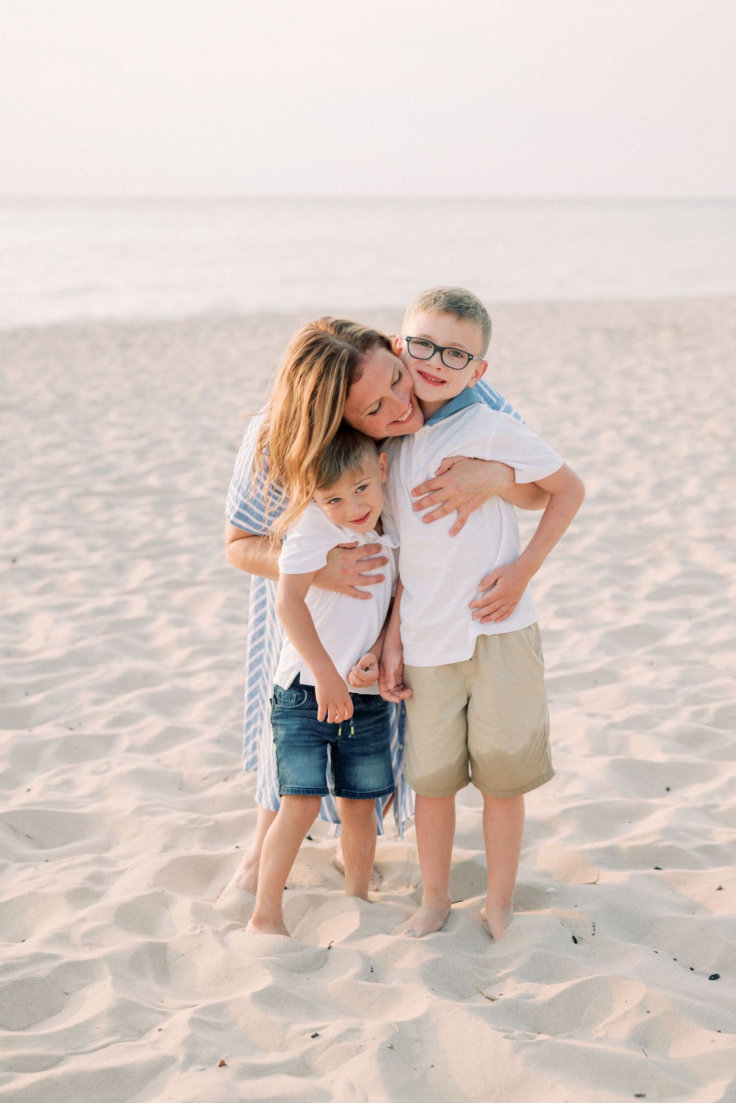 Loving embrace shared on a sunlit beach with waves in the background.