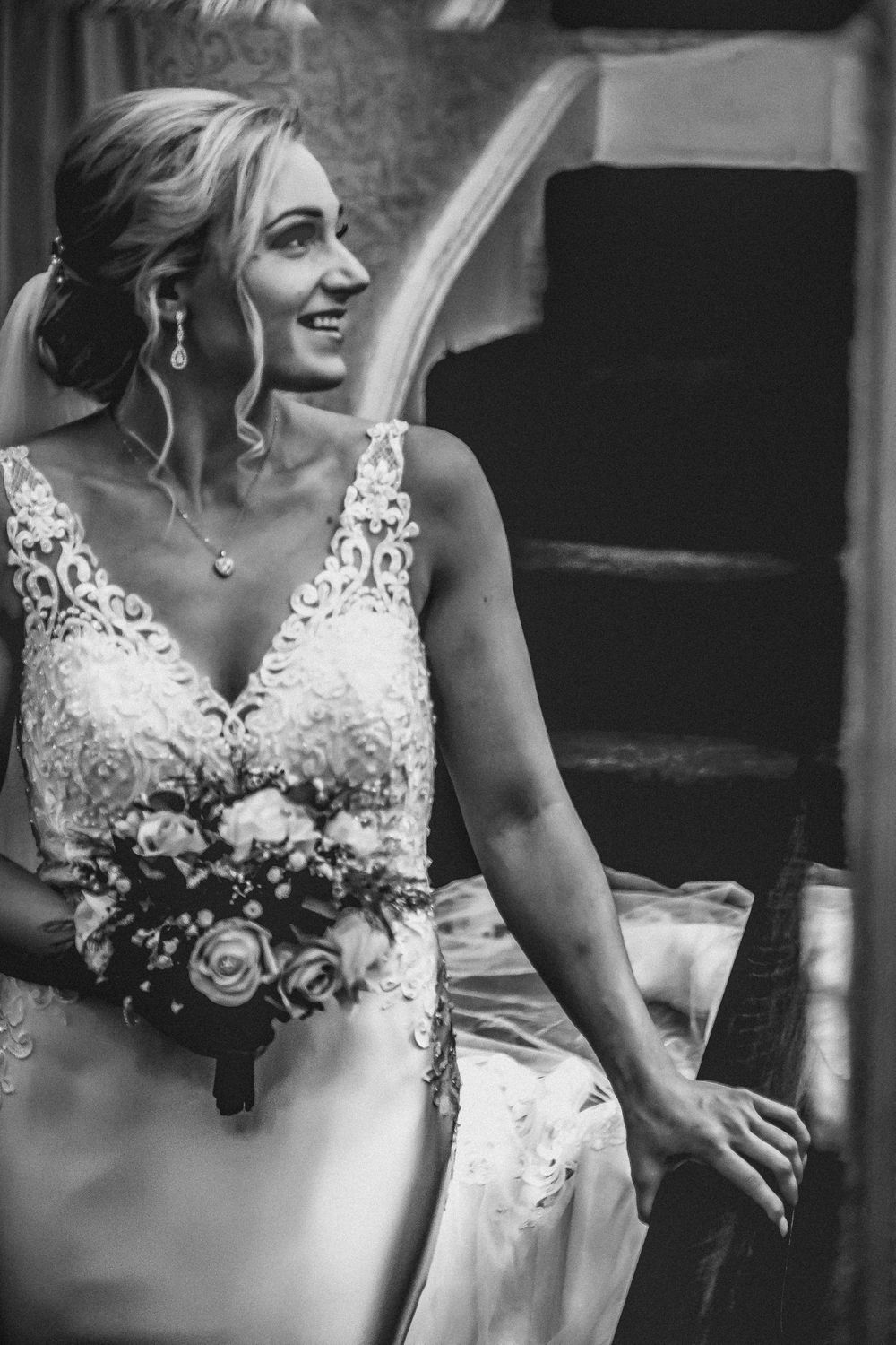 Black and white photo of Bride walking down stairs, reflected in mirror
