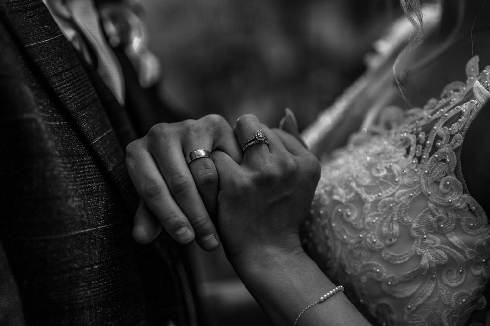 Black and white photo of bride and groom holding hands