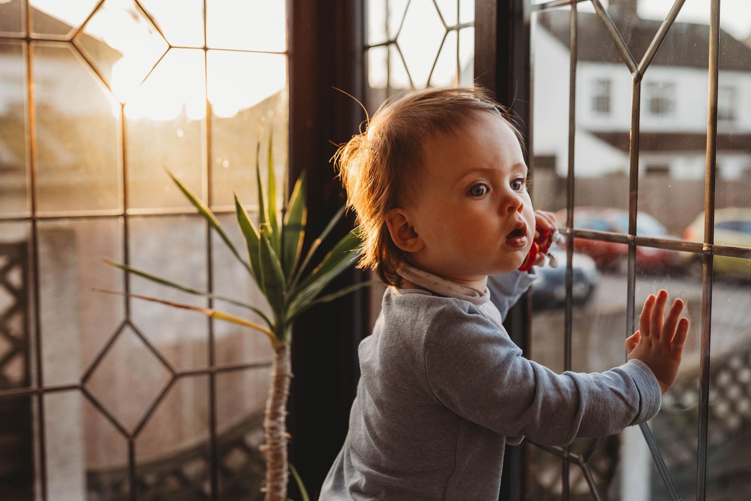 little baby girl looking out window golden hour
