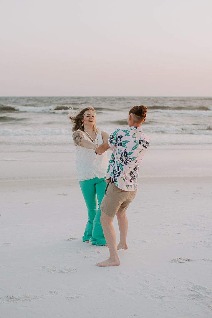 same sex couple spinning in a circle after their sunset Destin beach proposal