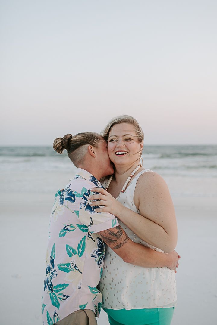 woman kissing her partners neck at sunset after they got engaged on a Florida beach