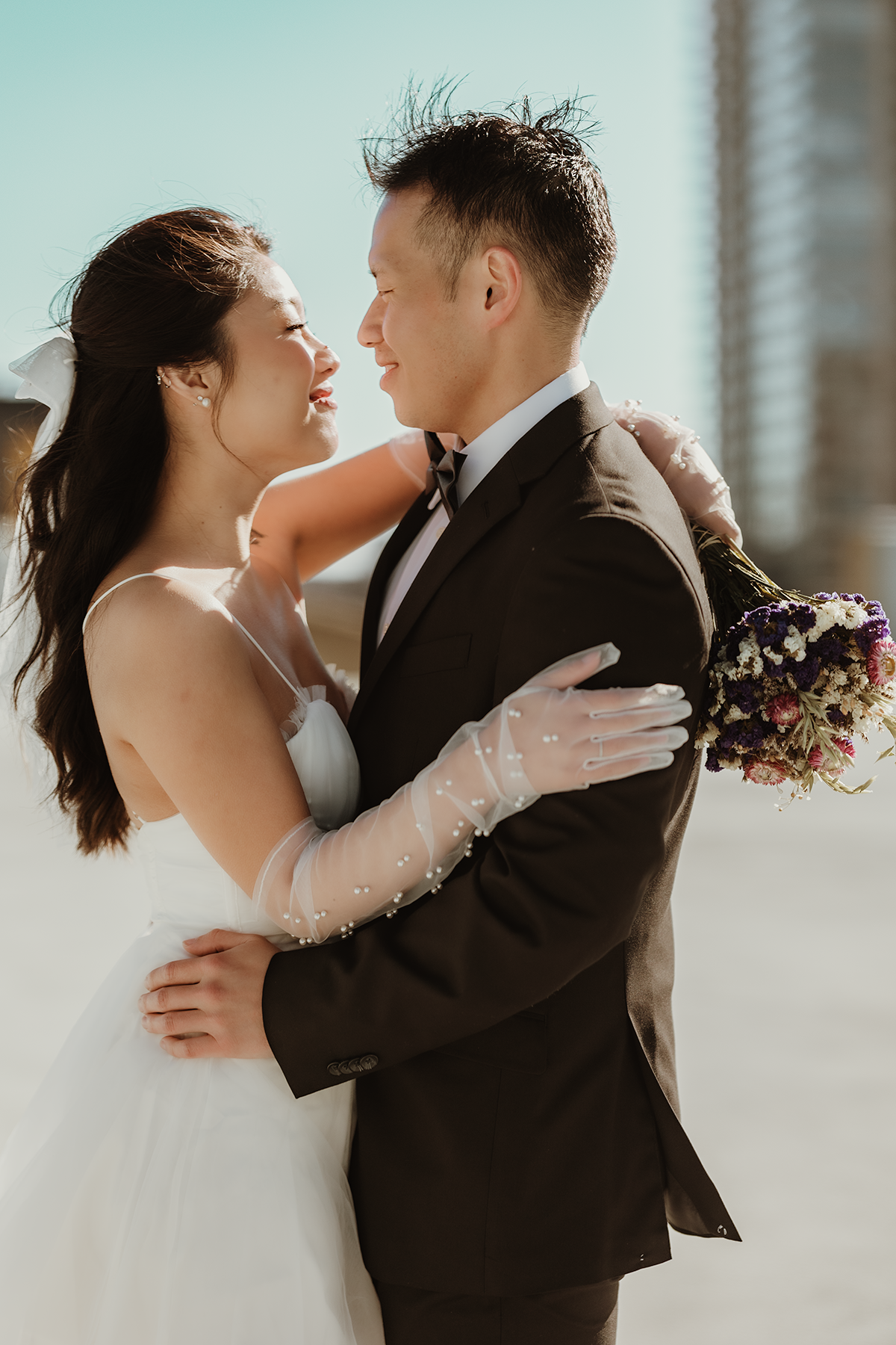 A romantic wedding moment captured with a bouquet and city skyline in the background.