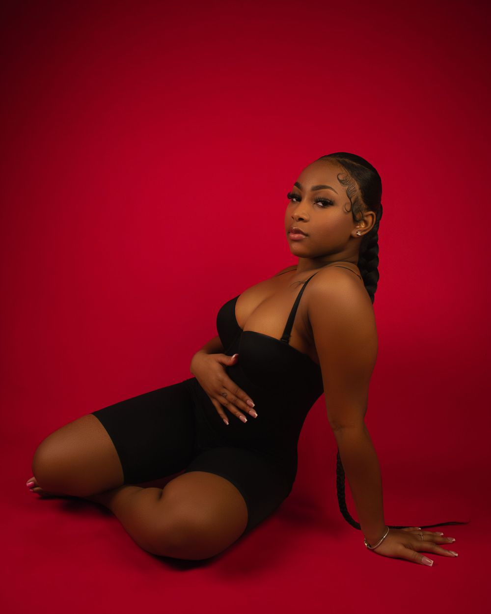 Professional studio portrait against vibrant red background in dramatic lighting.