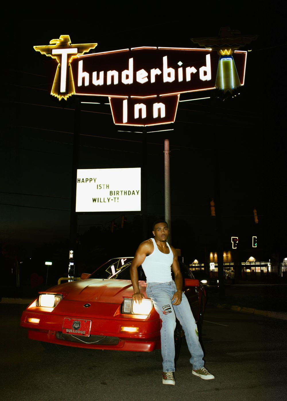 Vintage-style neon sign for Thunderbird Inn at night with red car parked beneath.
