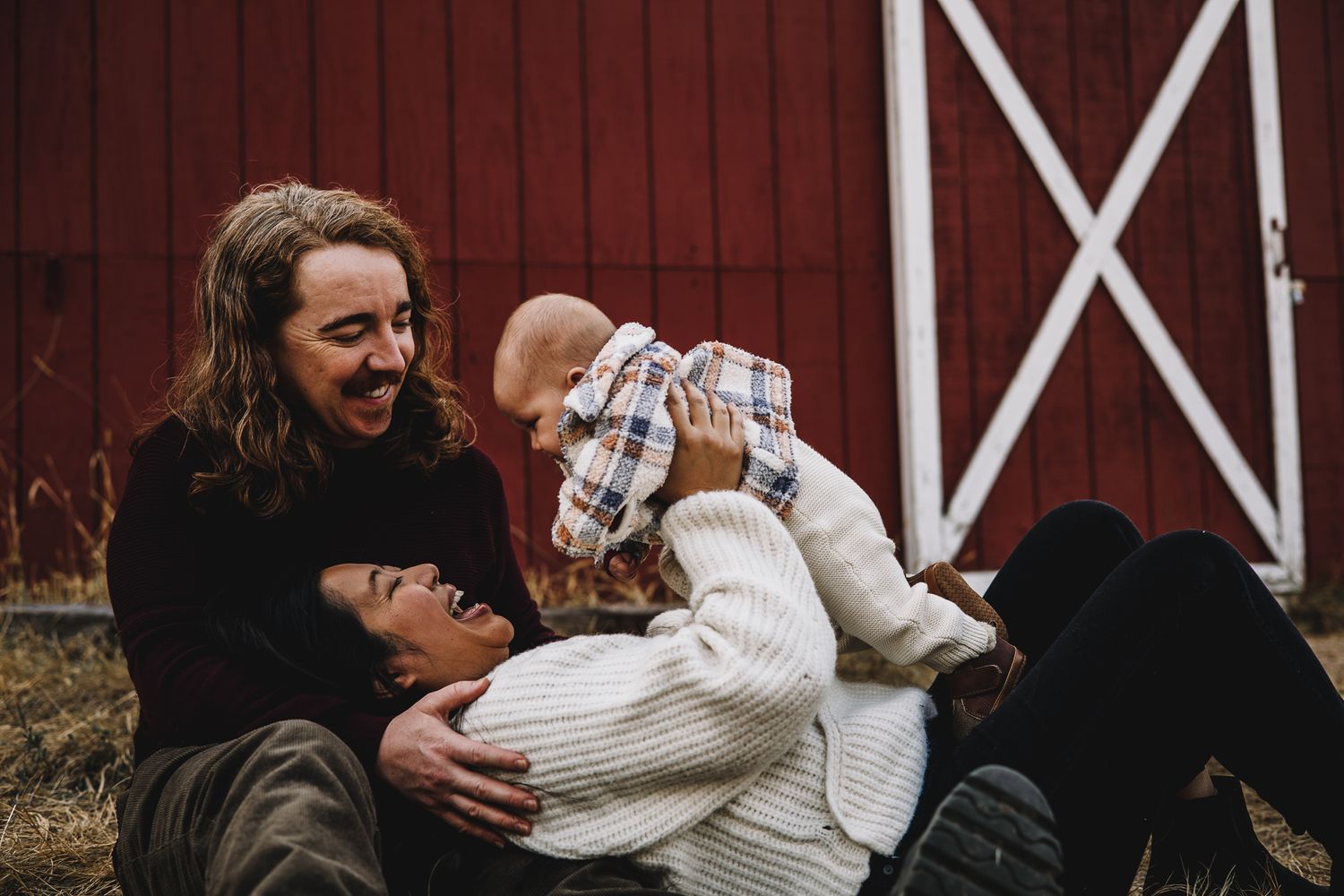 family of 3 posing with their baby smiling and having fun on the ground. liz rivas colorado photographer