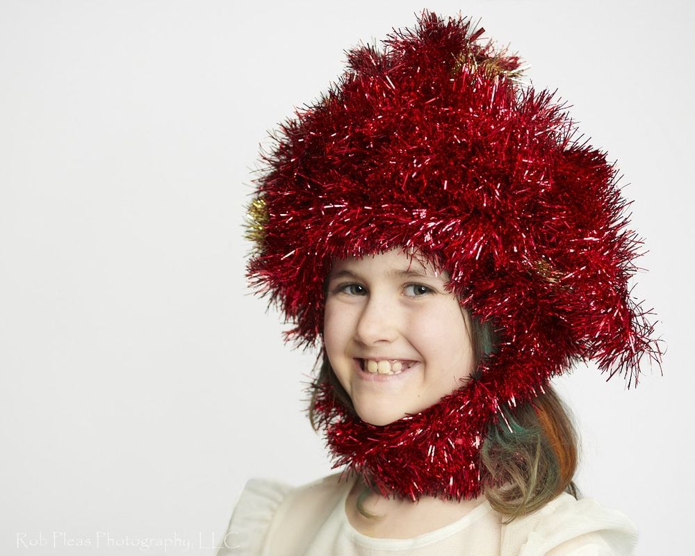 portrait of girl wearing headdress made of red garland from the Christmas tree