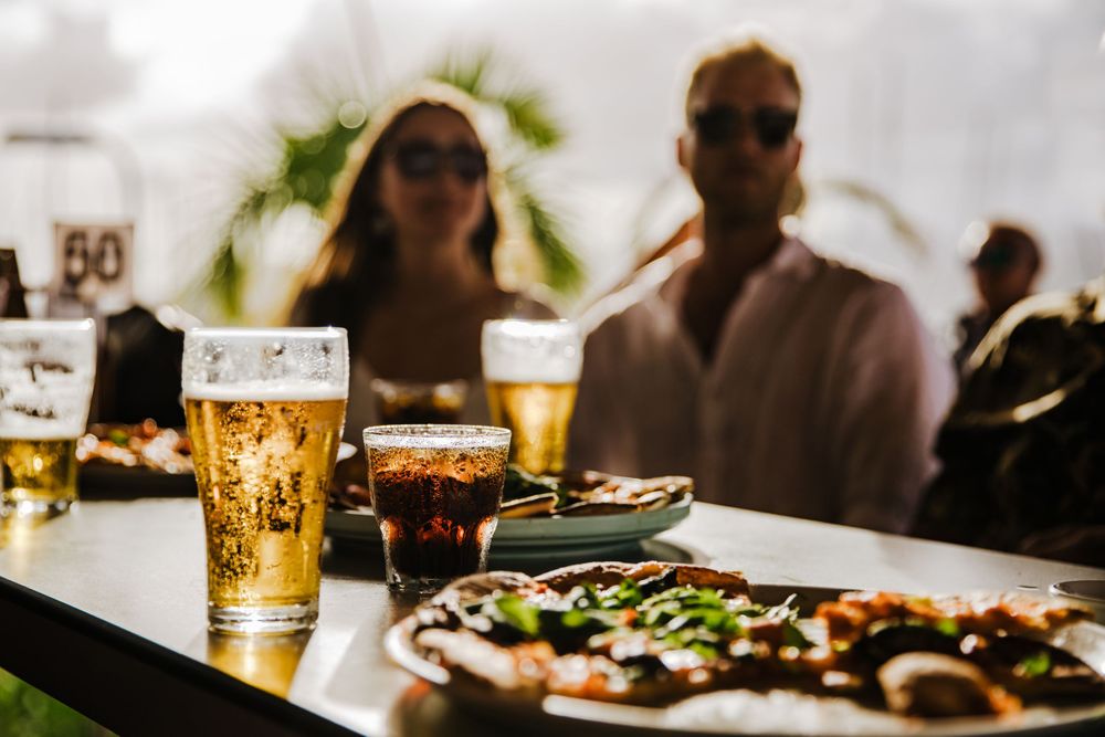beer and drinks on a table in foreground, backlit with patrons in background