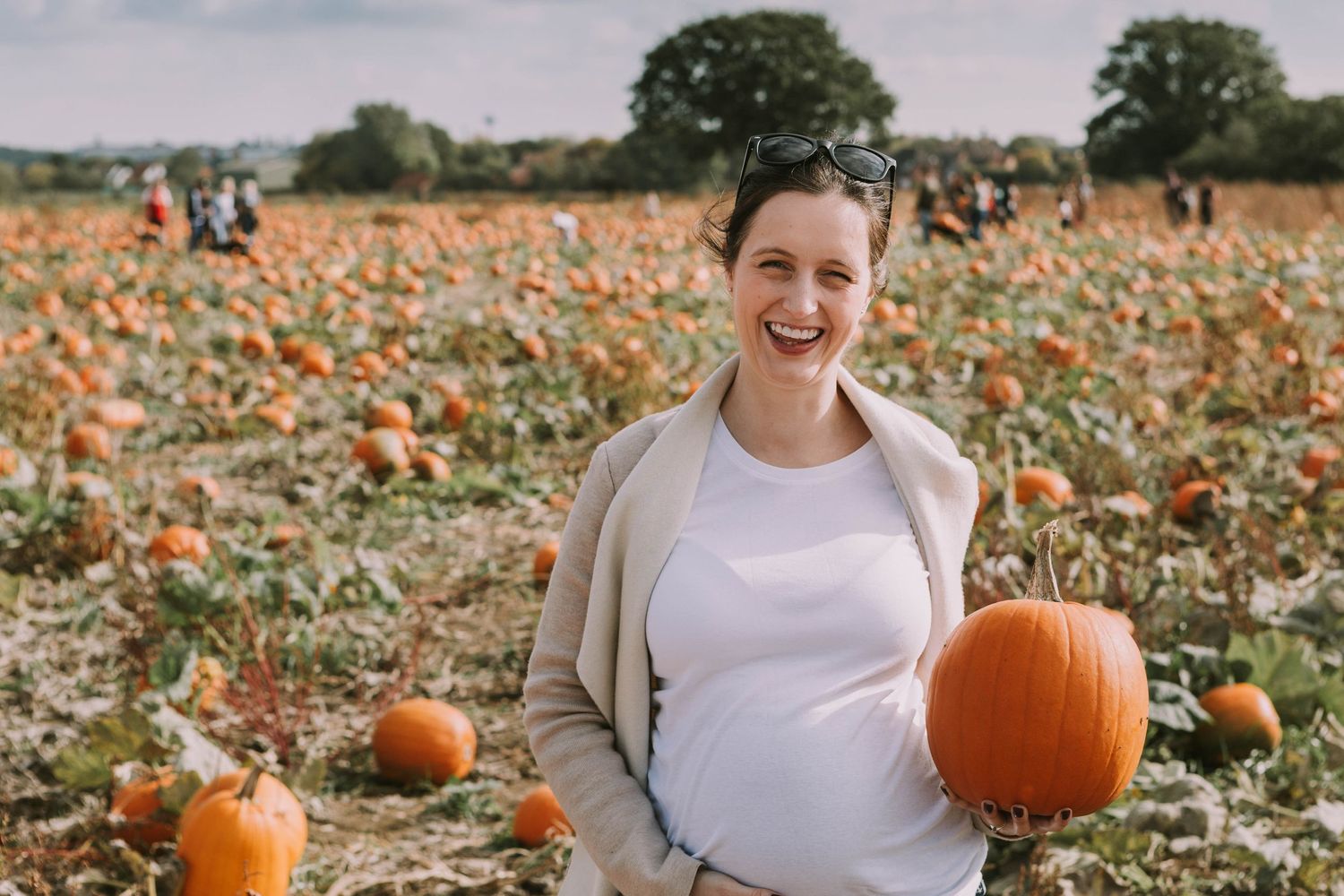 pregnant woman holding big orange pumpkin