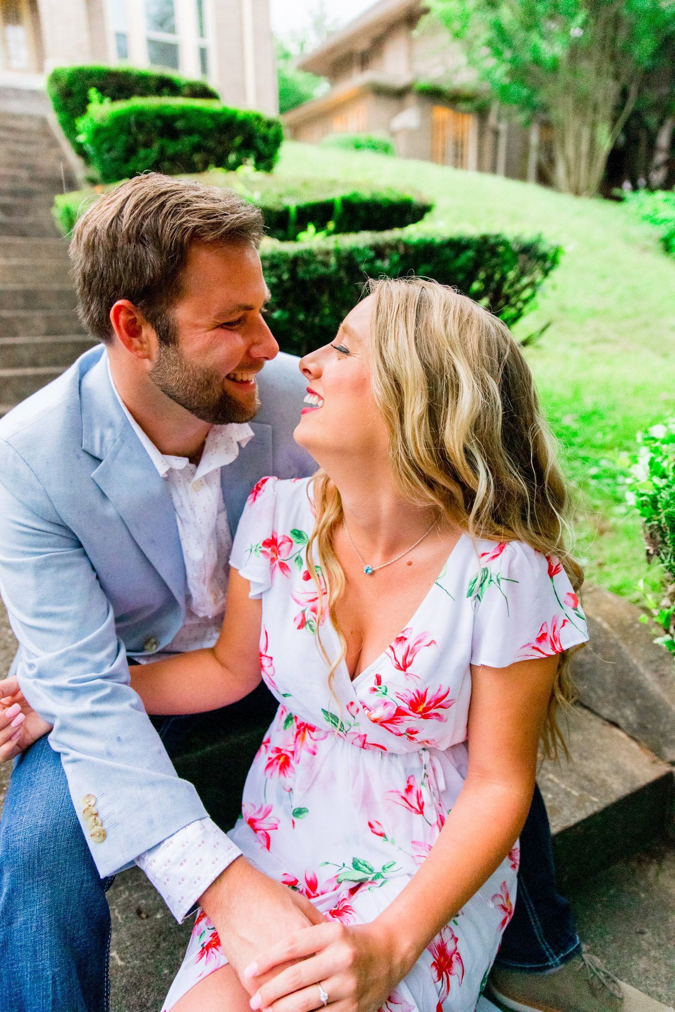 couple in floral dress and blue jacket sitting on steps and laughing with each other