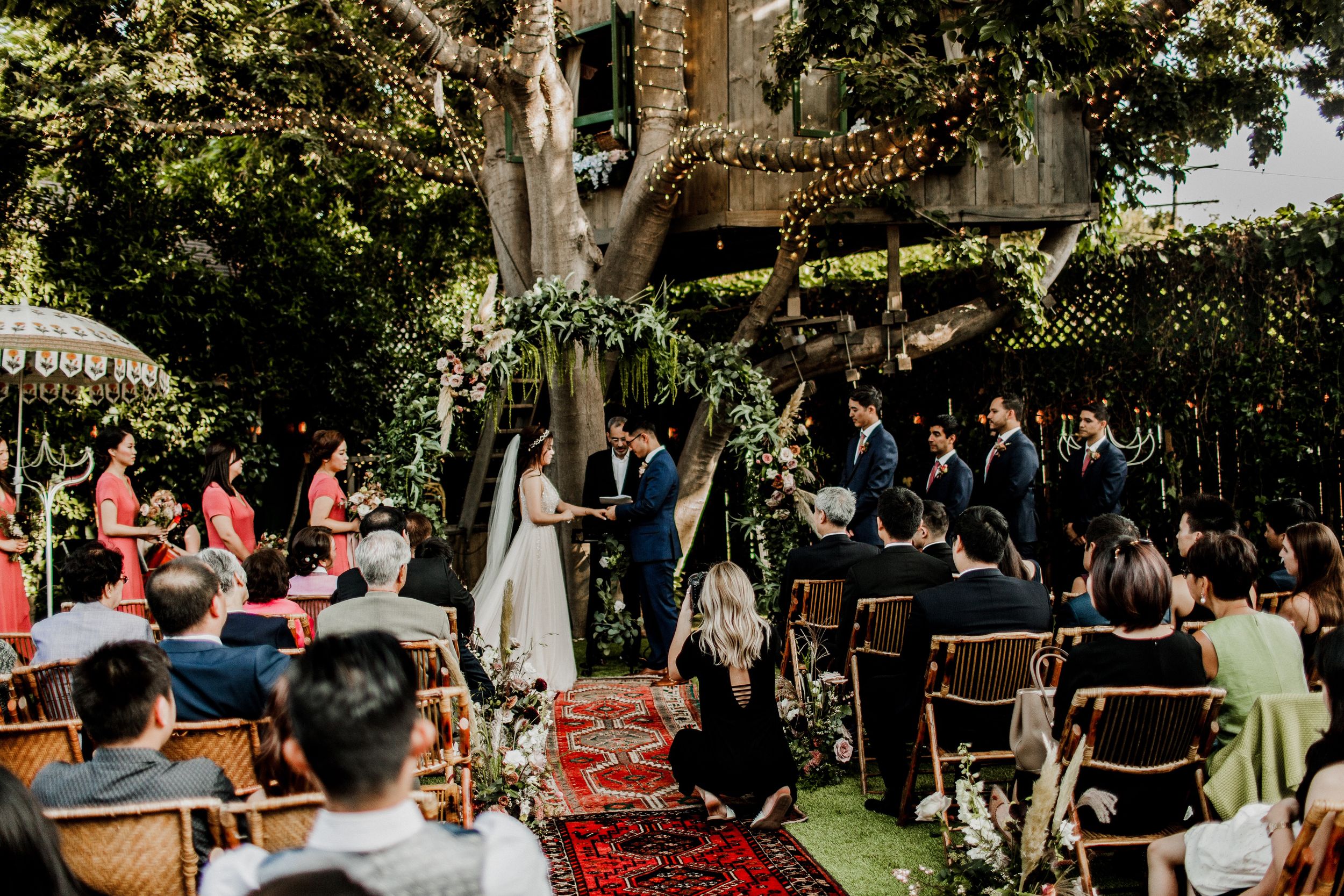 portrait behind the scenes of videography at wedding ceremony with treehouse background