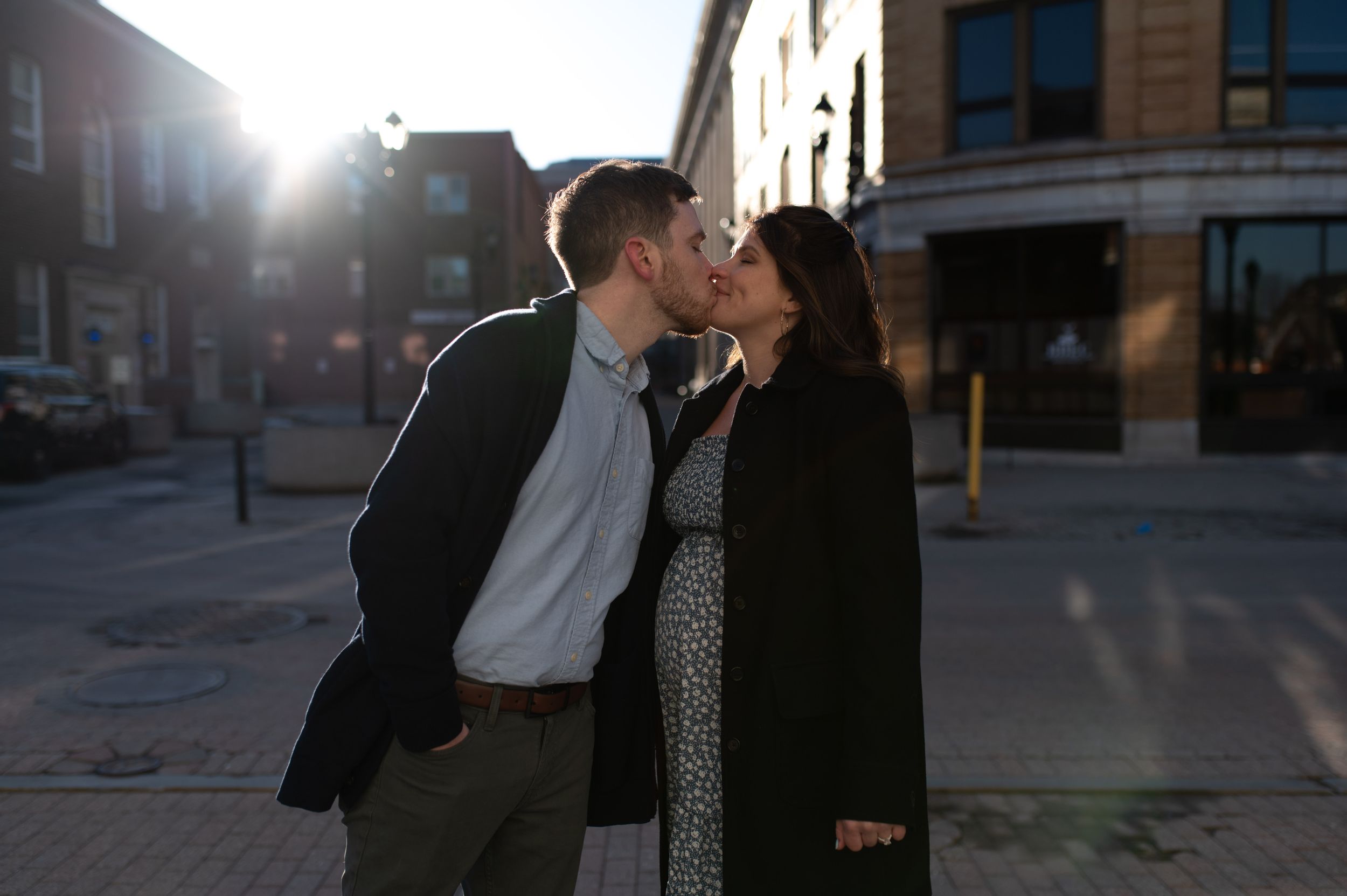 Silhouetted couple sharing a kiss at sunset in urban setting.