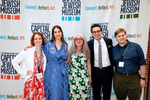 Five people pose together at a Jewish Museum event with branded banners in background.