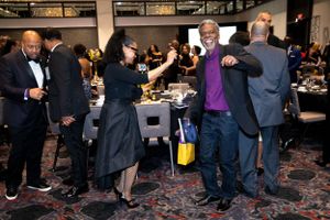 People dancing and socializing at a formal event with carpeted floors.