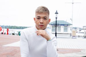 Portrait of person in white turtleneck sweater at waterfront location.