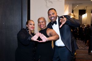 Group poses playfully making hand gestures at formal evening event.