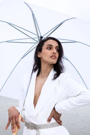 Stylish portrait with clear umbrella against waterfront backdrop.