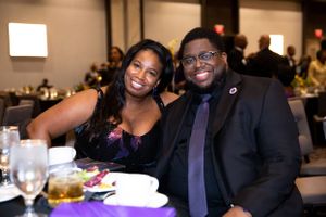 A couple dressed in formal attire enjoy dinner together at an elegant event.