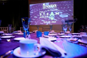 Elegant table setting with purple lighting and projection display at a formal event.