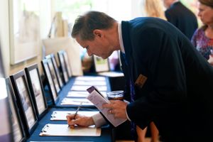Guest writing bid on auction form at formal charity event.