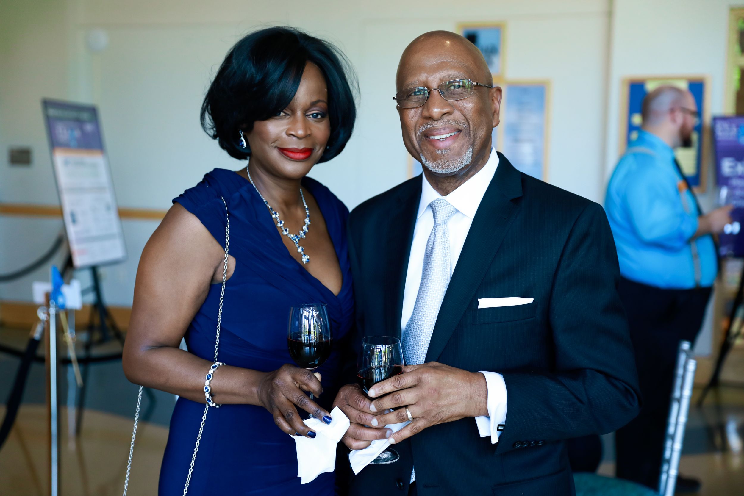 Elegant couple in formal attire sharing drinks at an indoor social event.