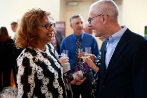 Two people chatting and holding drinks during a social gathering in an indoor venue.