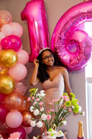 Festive party scene with large pink number balloons and floral decorations.