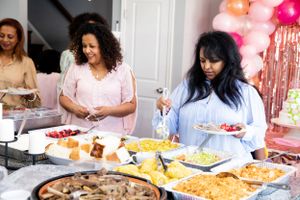 Festive buffet spread with multiple dishes and pink balloon decorations.