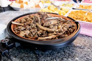 Large platter of grilled or sauteed meat served at a buffet.
