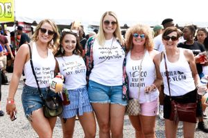 Group wearing matching t-shirts poses together at an outdoor festival.