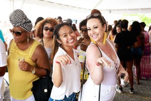 Festival attendees enjoying themselves under a white tent at summer event.