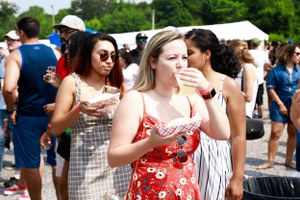 Festival attendees enjoying a sunny outdoor event with drinks and live music.