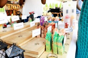 Colorful bottles and drink mixers displayed on wooden shelves at an outdoor bar.