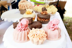 Assorted gourmet mini desserts and pastries decorated with chocolate and pink frosting.