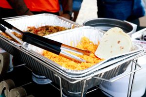 Serving trays filled with Mexican food including rice and tortillas at a catering event.