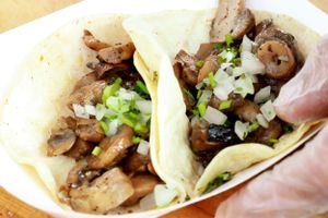 Close-up of mushroom tacos topped with fresh lettuce and onions in soft tortillas.