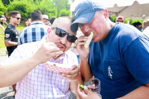 Attendees enjoying food samples at an outdoor festival on a sunny day.