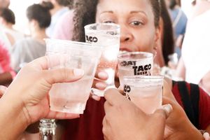 Group of people toasting with clear plastic cups at an outdoor event.