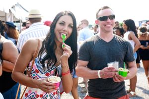 Two festival-goers enjoying drinks and snacks at an outdoor summer event.