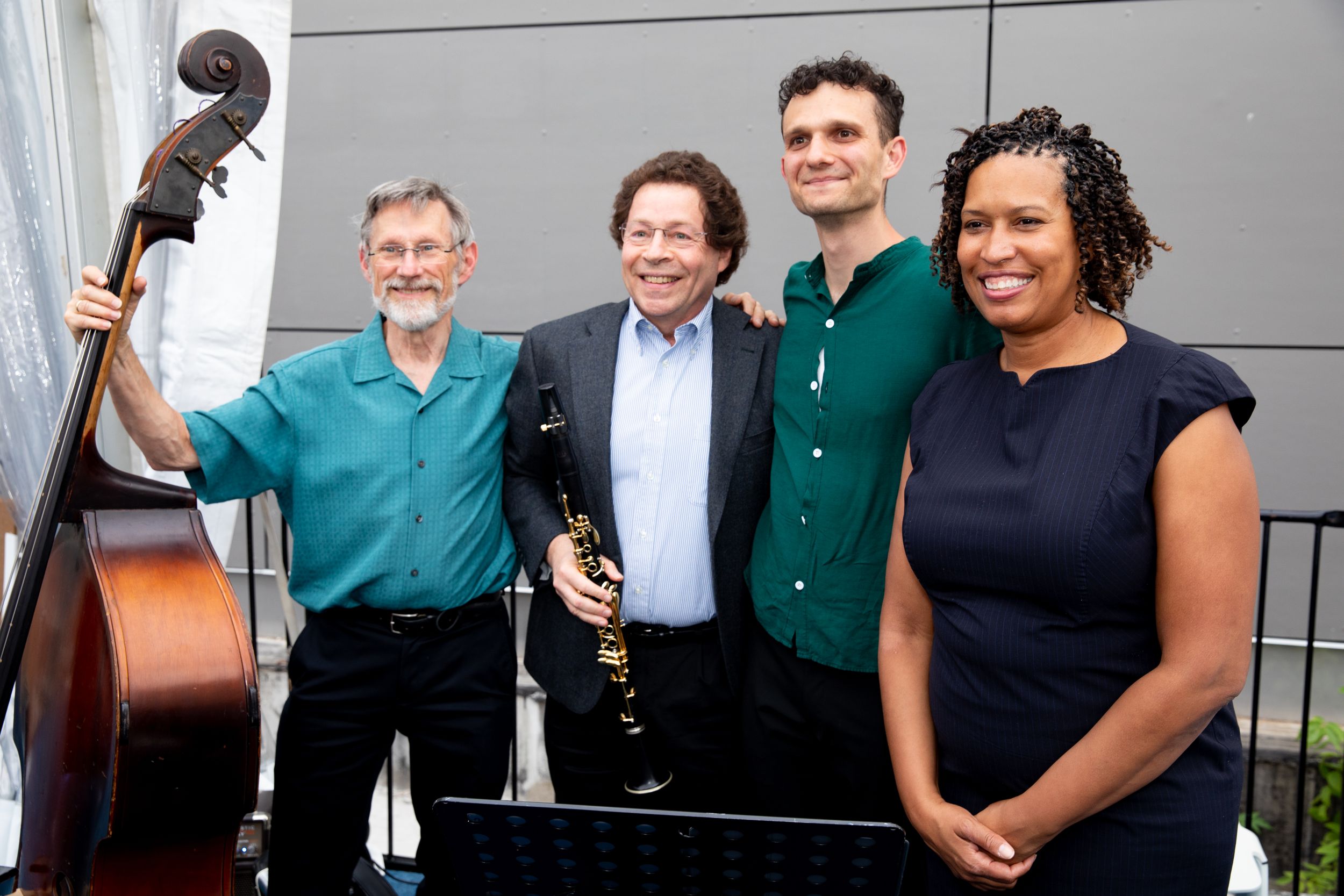 Musicians pose together with instruments at a performance event with Mayor Muriel Bowser.