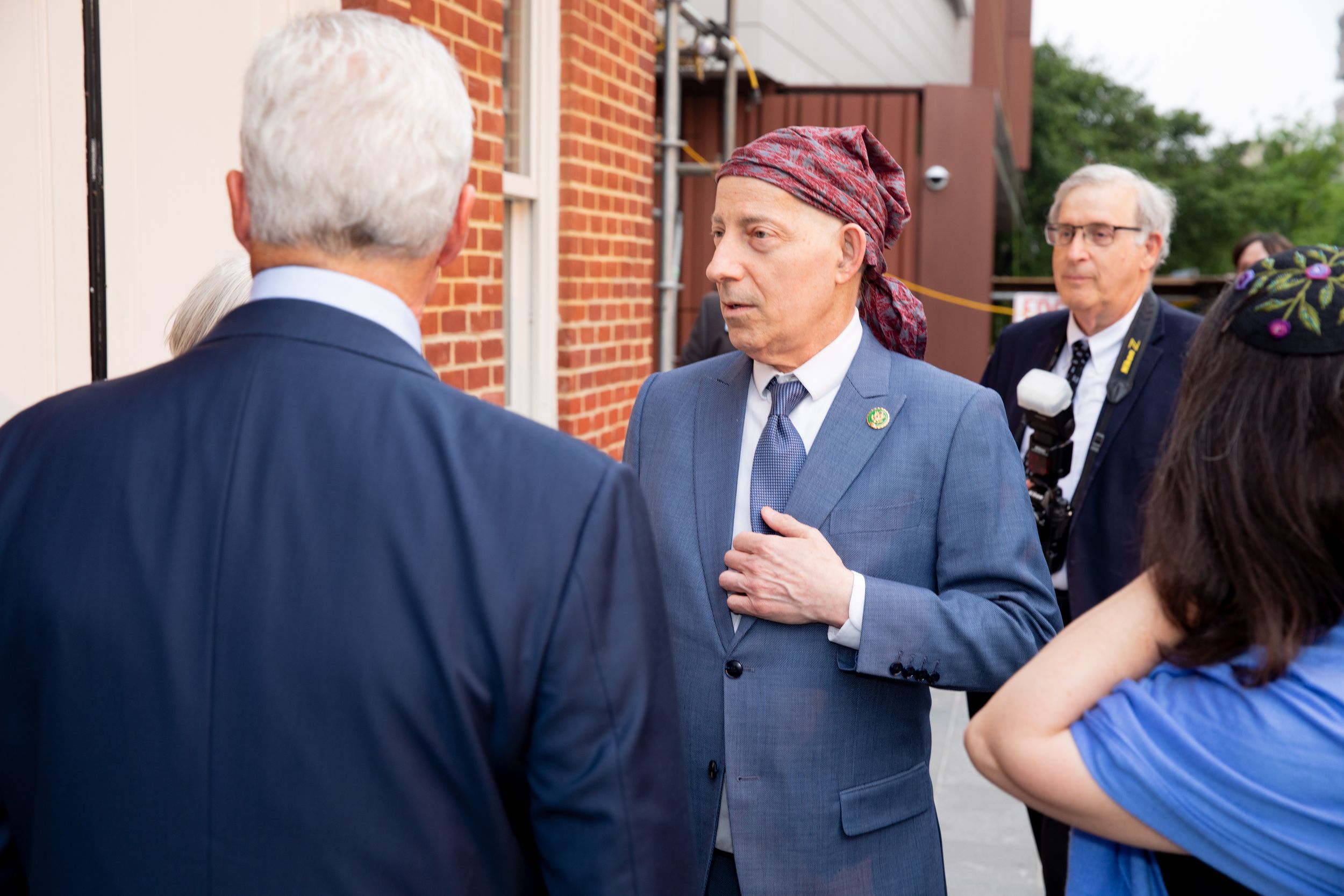 Event attendees engage in conversation while standing near a brick building.