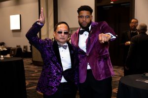 Two attendees in purple formal attire pose together at evening gala event.
