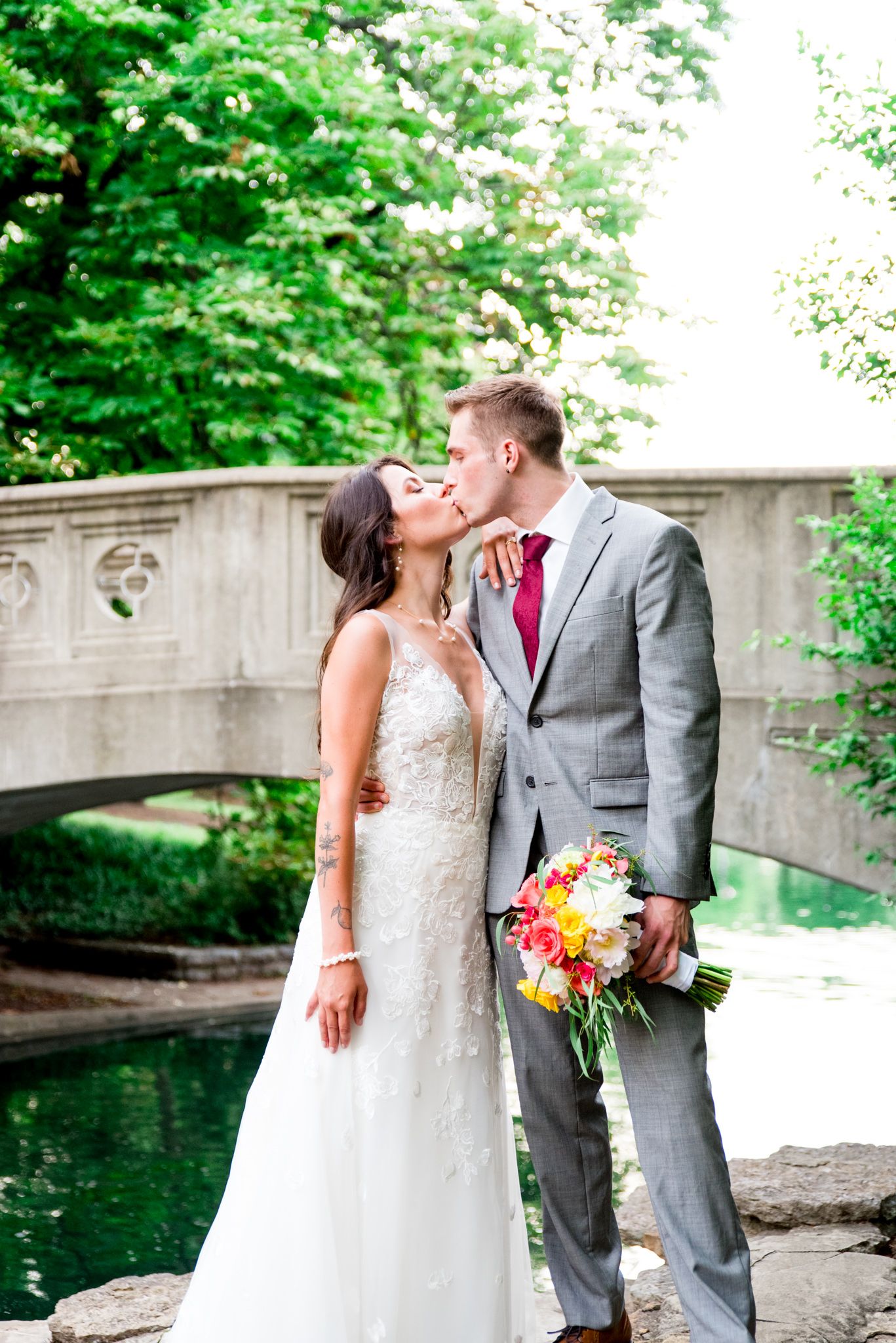 bride in Kelly Faetanini Serafina gown kissing groom in gray suit at Eden Park bridge in Cincinnati wedding