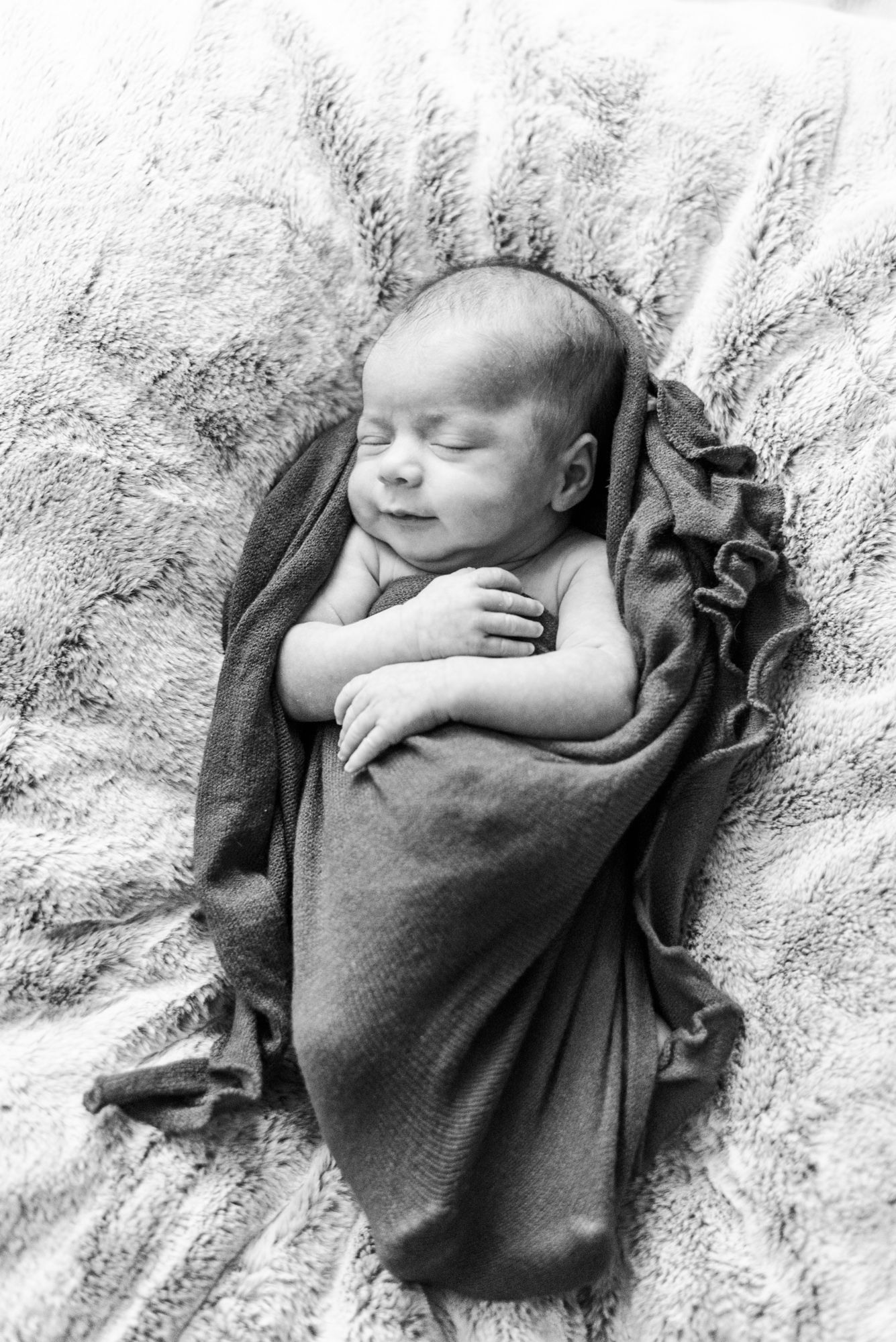 Lifestyle newborn baby laying in wrap smiling in black and white in Pittsburgh, Pennsylvania