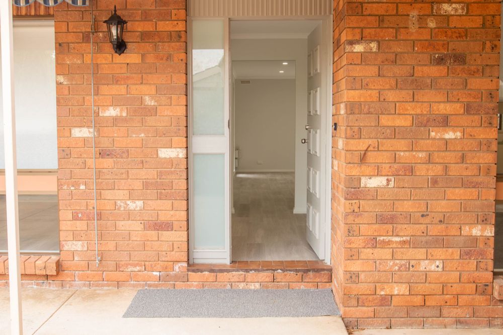 Close-up of brick entrance with modern glass door and wall-mounted lantern.