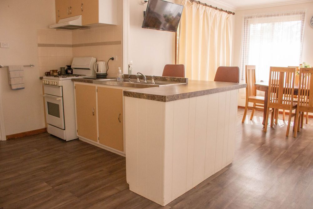Open concept kitchen with light wood cabinets, gas stove, and dining area visible in background.