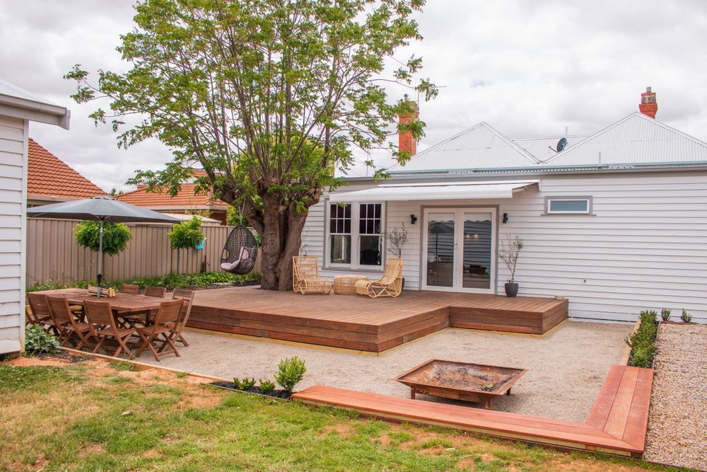 Spacious backyard deck with outdoor dining furniture and mature tree providing natural shade.