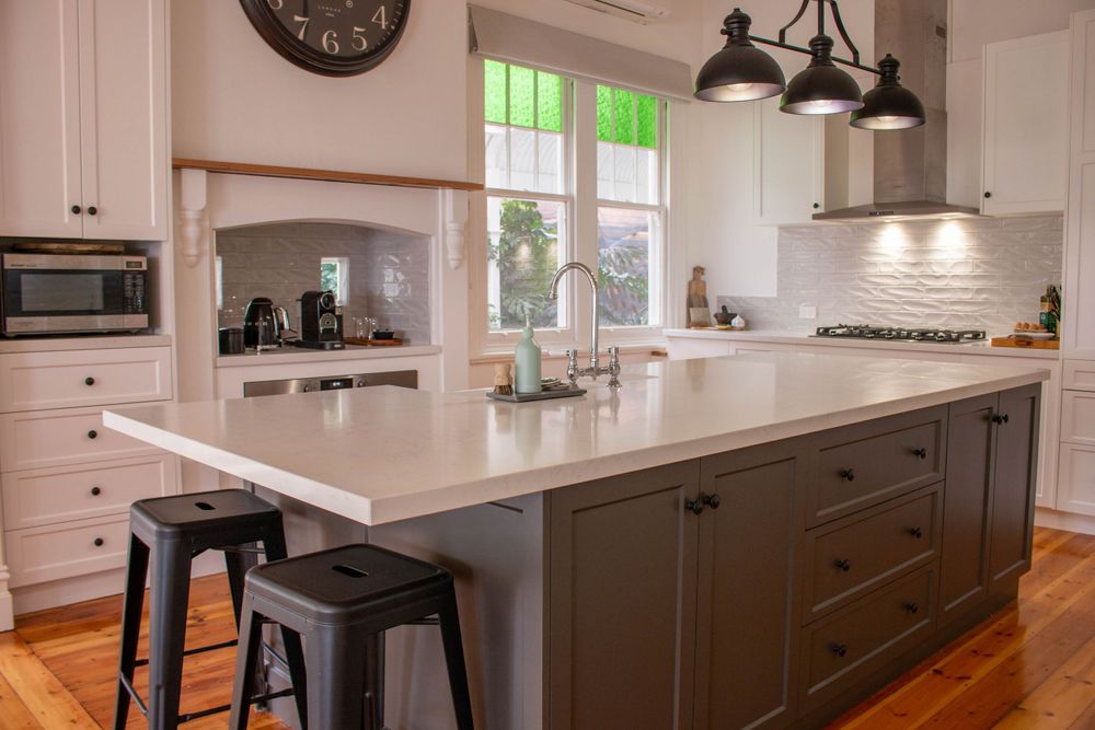 Modern kitchen featuring white cabinets, large island with bar stools, and pendant lighting.