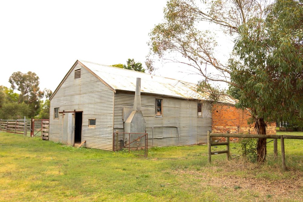 Rustic wooden barn building with metal roof in rural countryside setting.