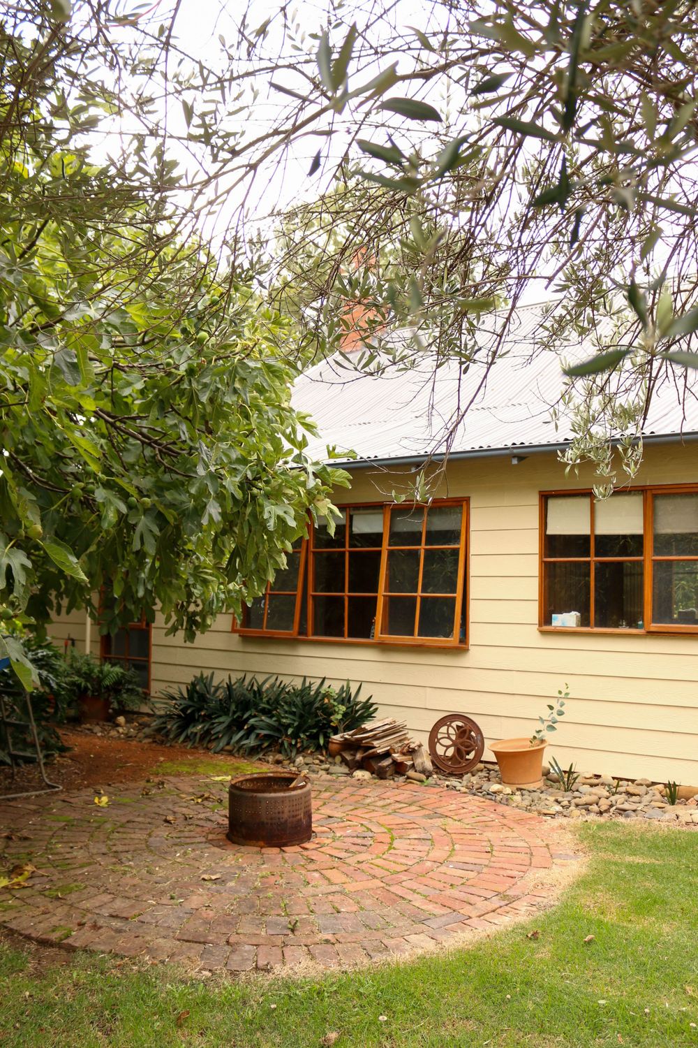 Yellow house exterior with brick pathway and garden features.